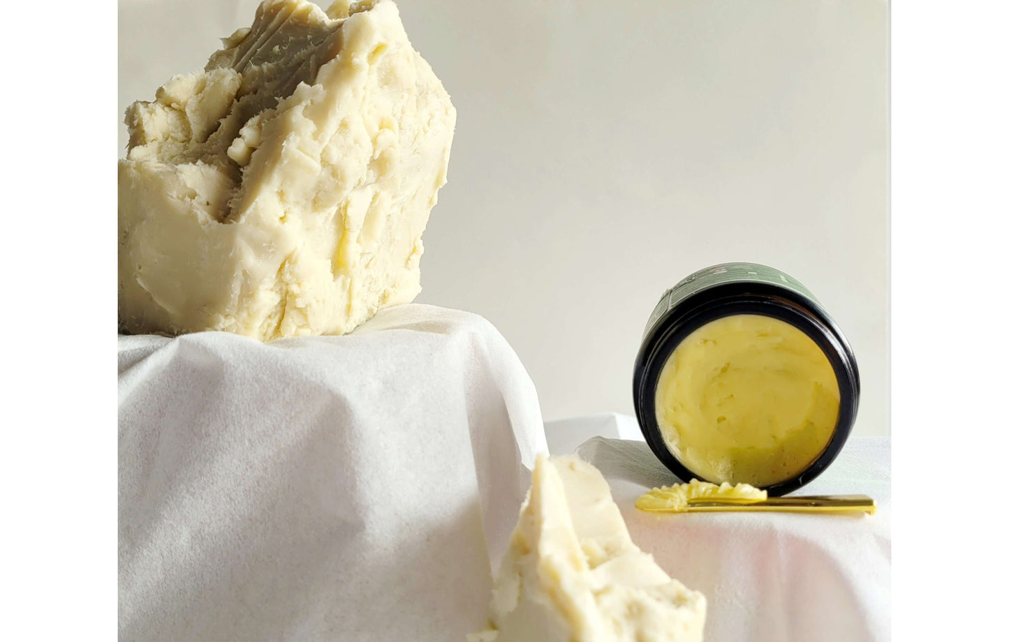 A block of raw shea butter with an open jar of Wild Roots Body Butter-Wild Lavender